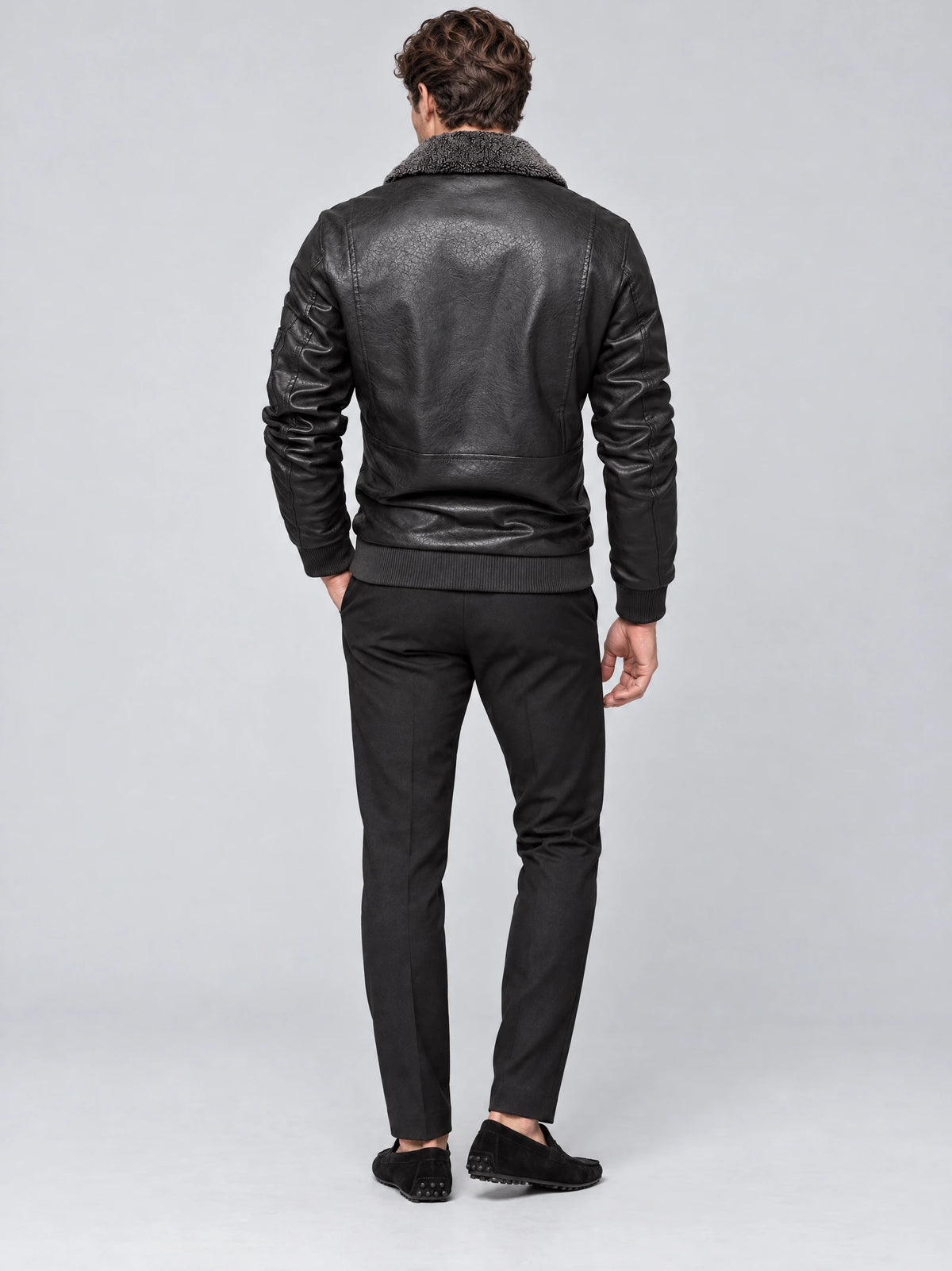 Rear studio view of a model wearing a Gray Leather Aviator Jacket with a textured collar, paneled back, and ribbed hem.