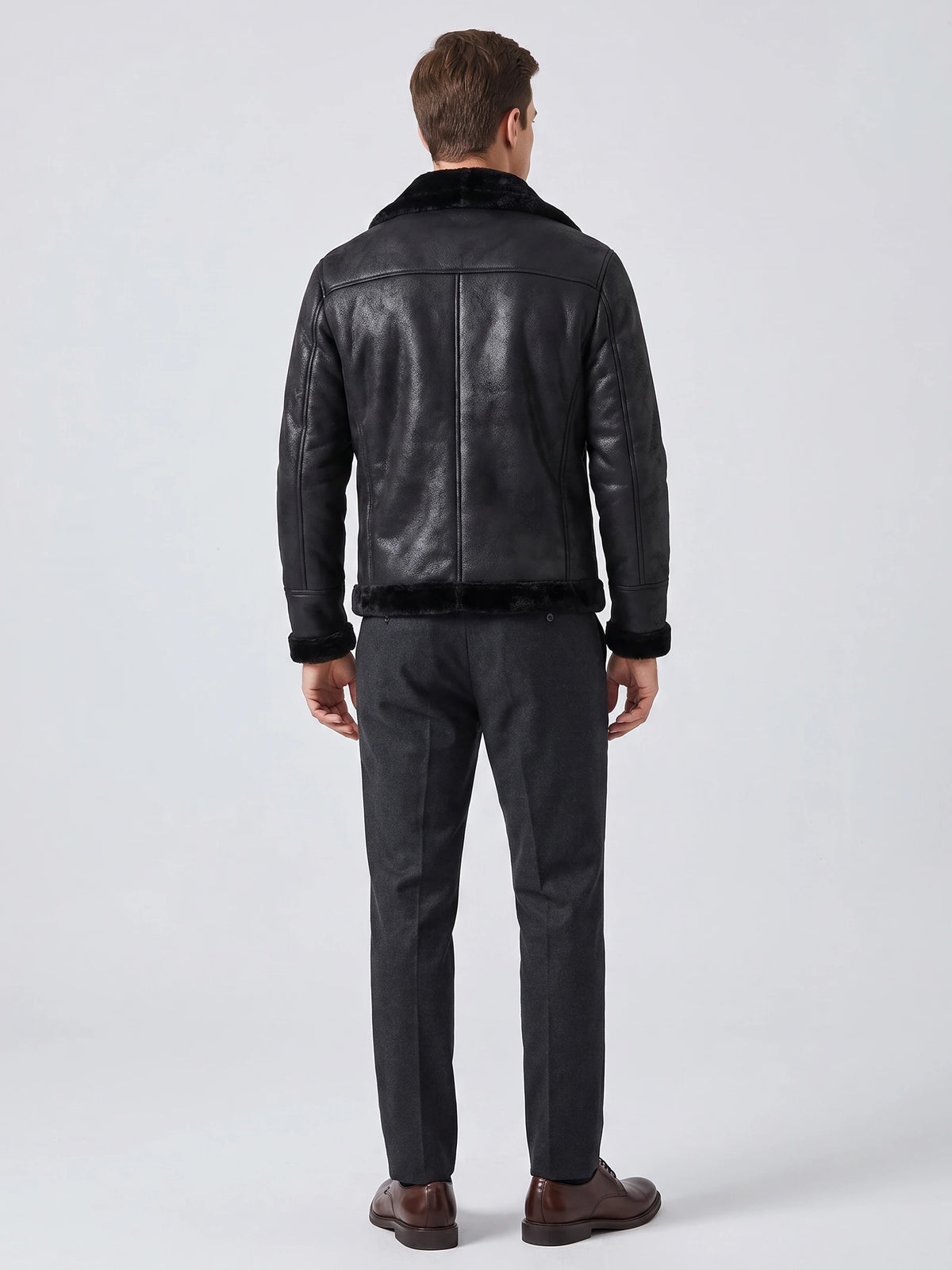 Rear studio view of a model wearing a Black aviator-style PU leather jacket with a plush collar, trimmed hem, and cuffs.