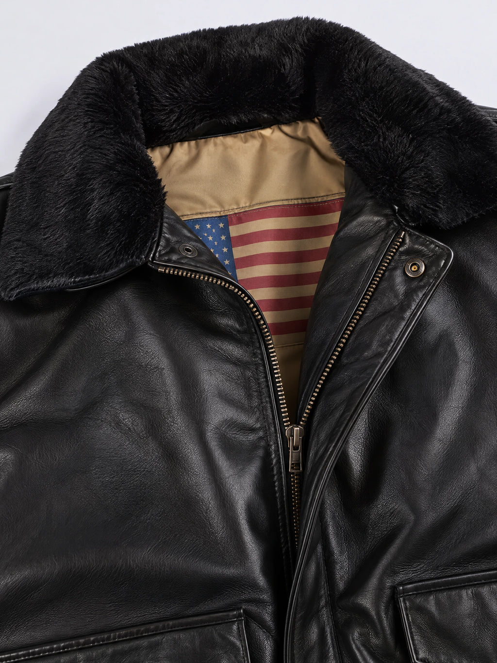 Close-up of a Black Leather Bomber Jacket with a plush collar, front zipper, snap tab, and patterned inner lining.