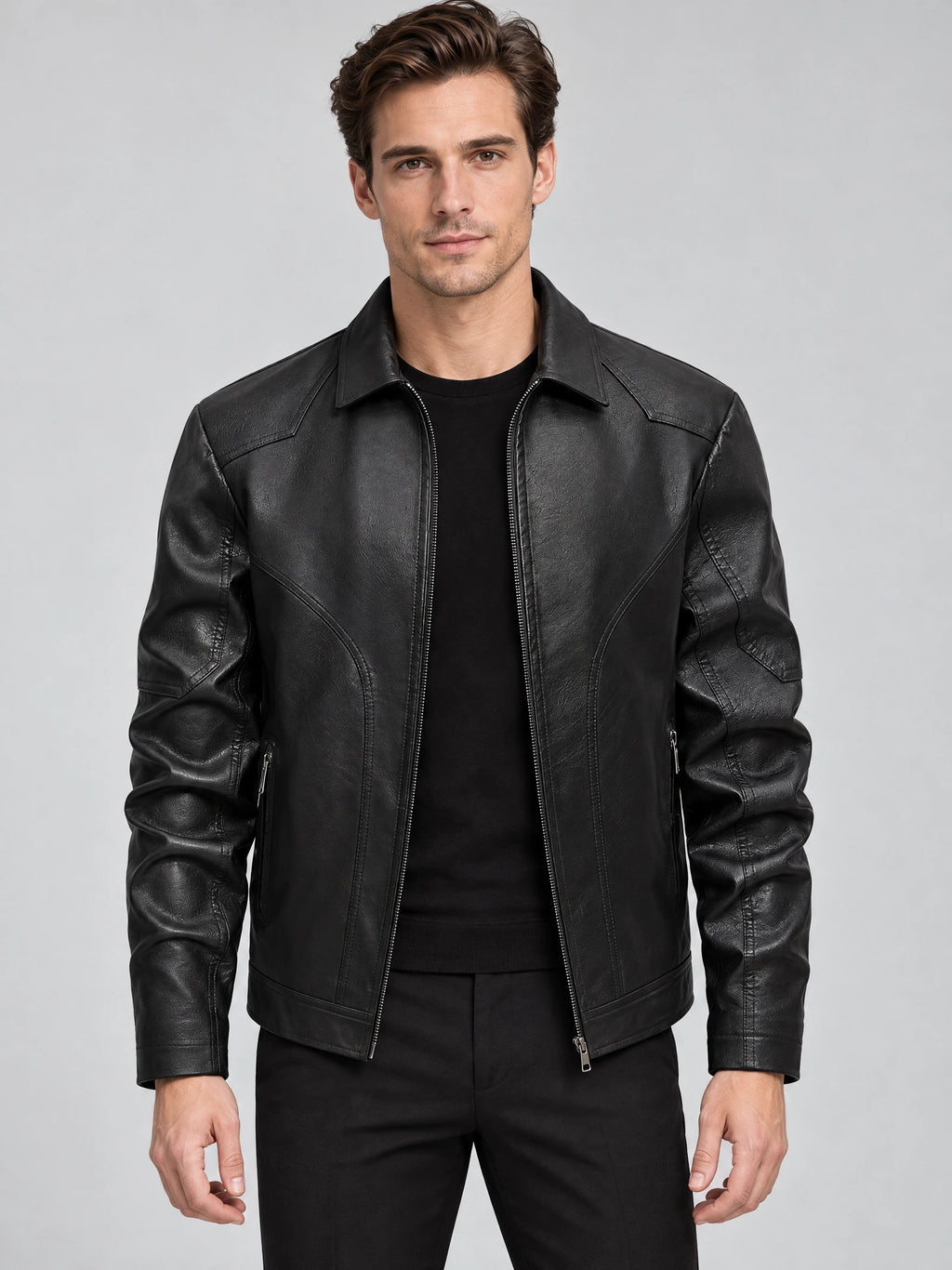 Front studio view of a model wearing a Black leather bomber jacket with a zip front, pointed collar, and zippered pockets.