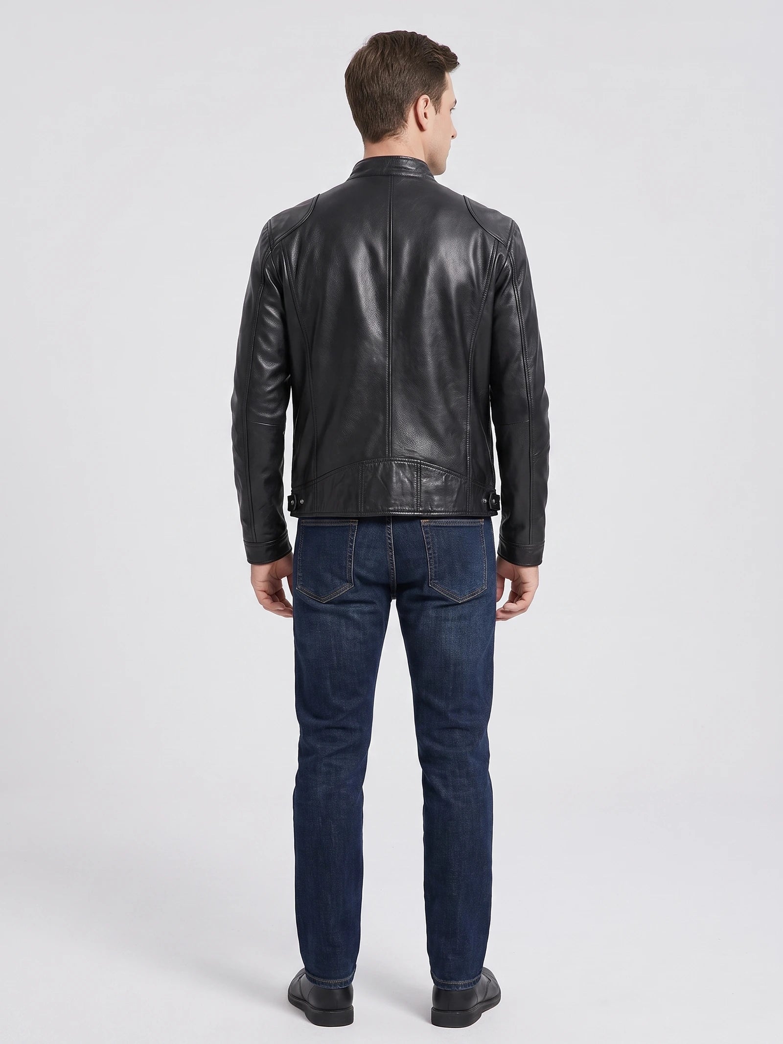 Rear studio view of a model wearing a Black Men's Leather Jacket with paneled back stitching and adjustable side tabs.
