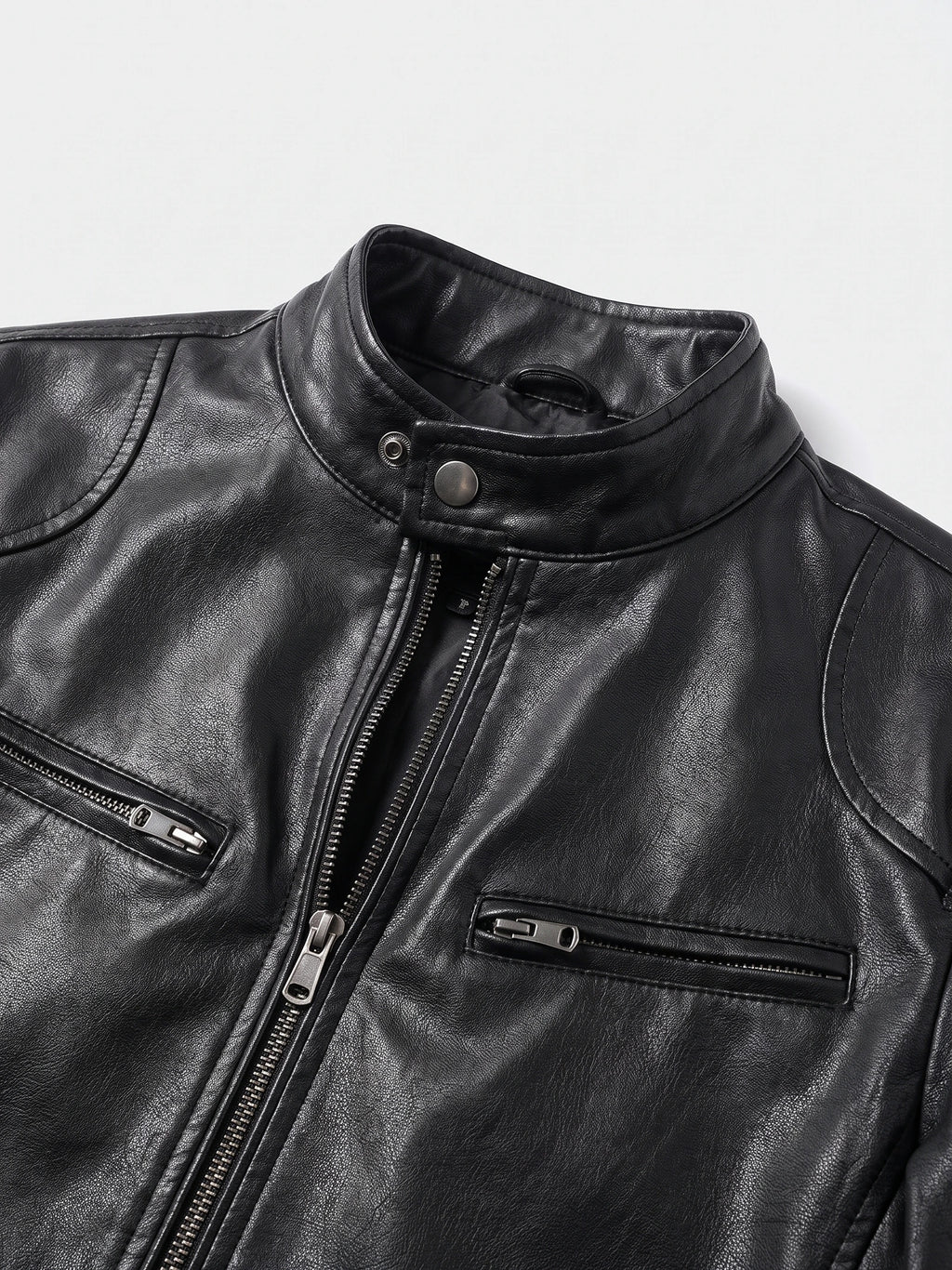 Close-up of a Black men's leather jacket with a snap-tab stand collar, front zipper, and zippered chest pockets.