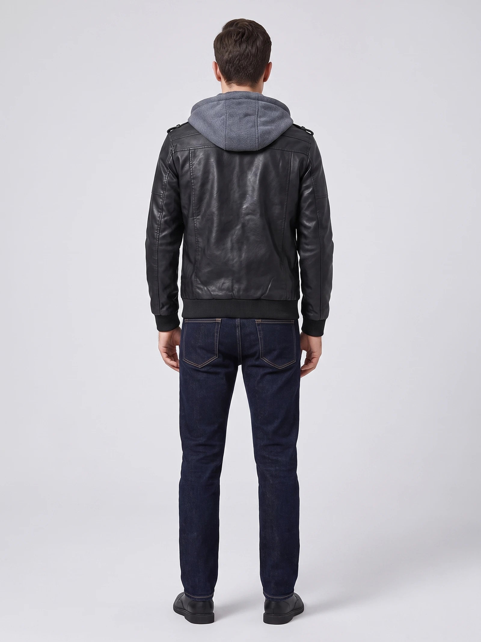 Rear studio view of a model wearing a Black mens leather jacket with a hood, shoulder tabs, and ribbed hem and cuffs.