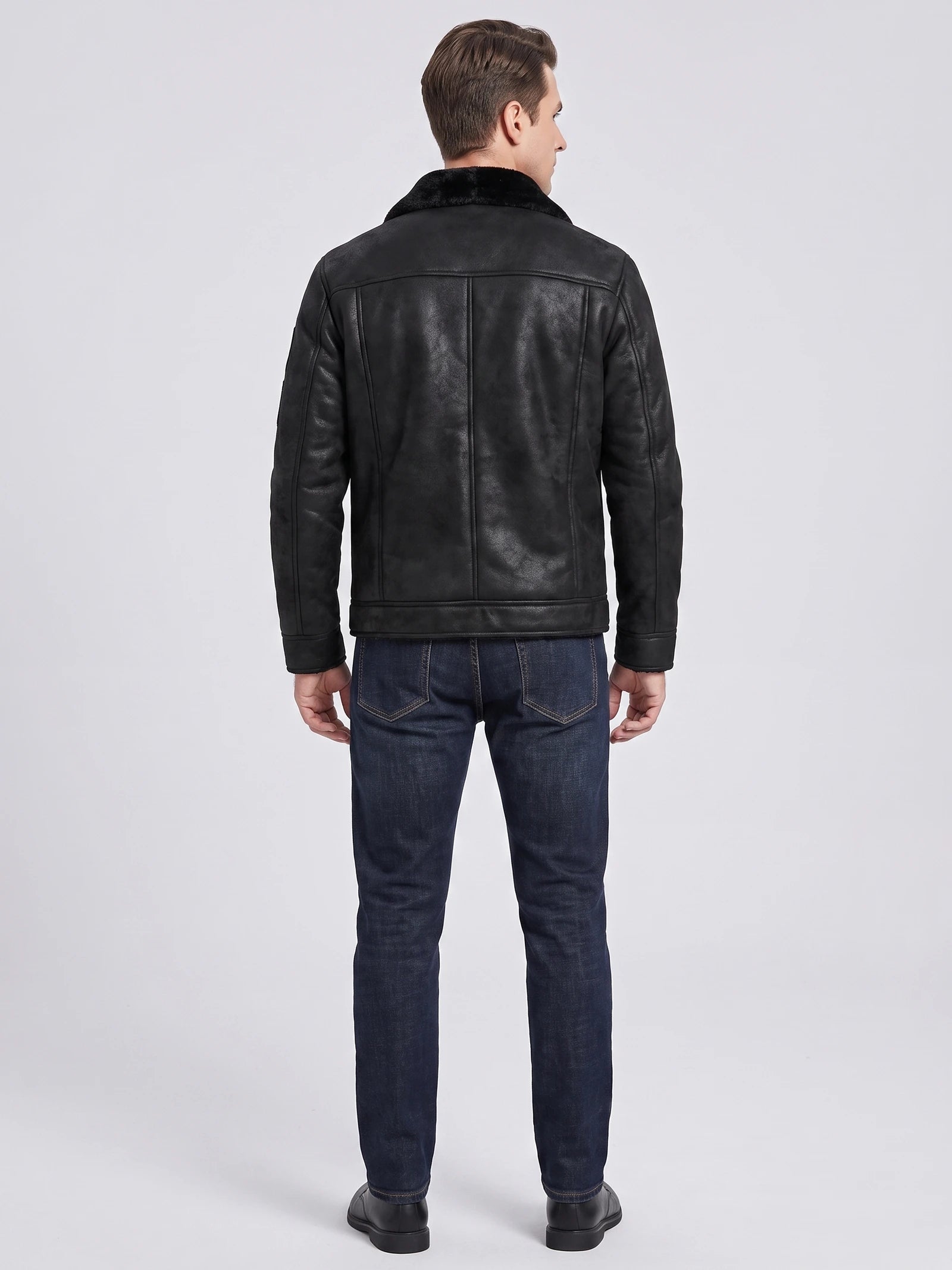 Rear studio view of a model wearing a Black leather jacket with a plush collar and paneled back stitching.