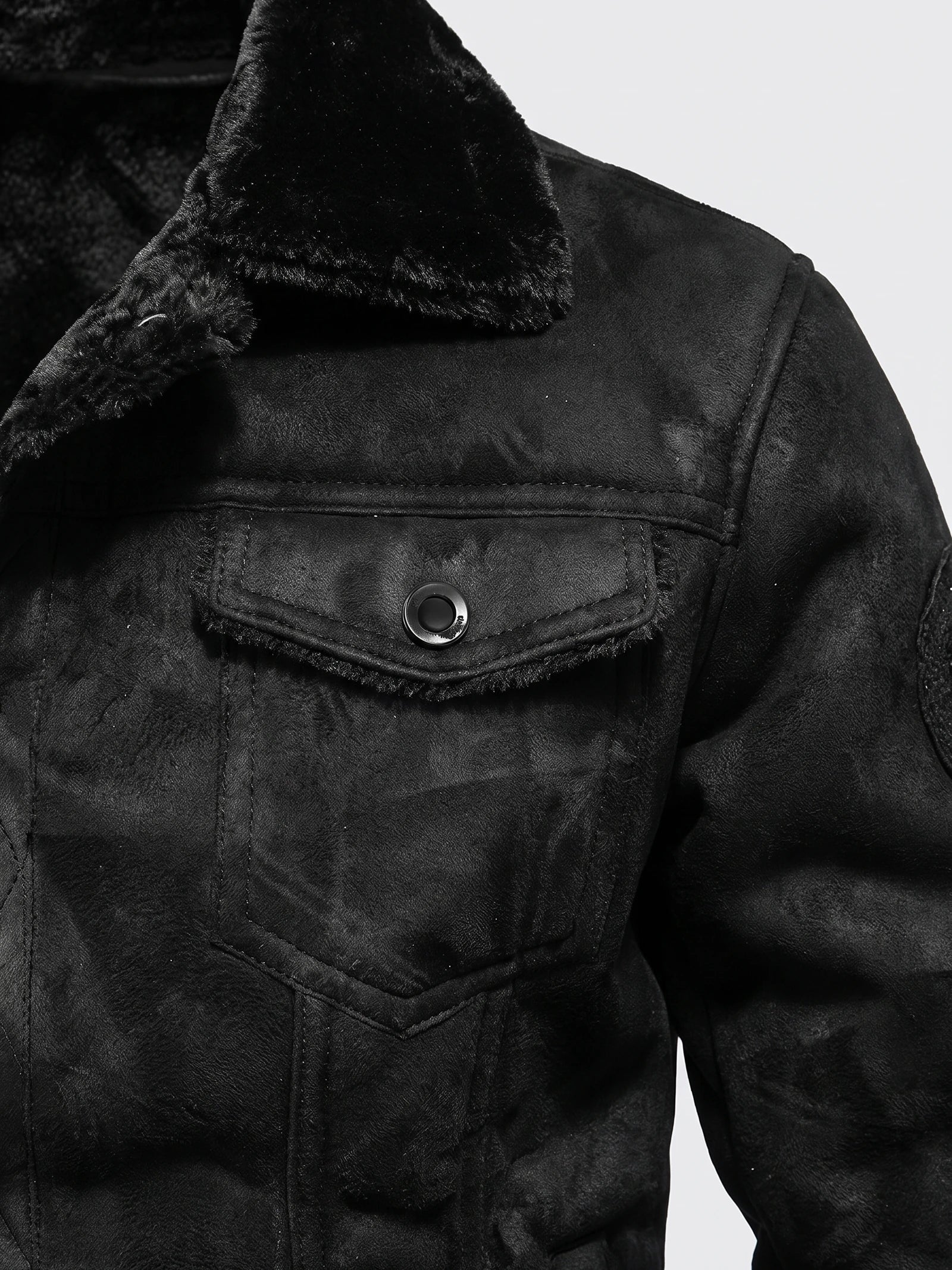 Close-up of a Black men’s leather jacket with a fleece-lined collar and buttoned flap chest pocket.
