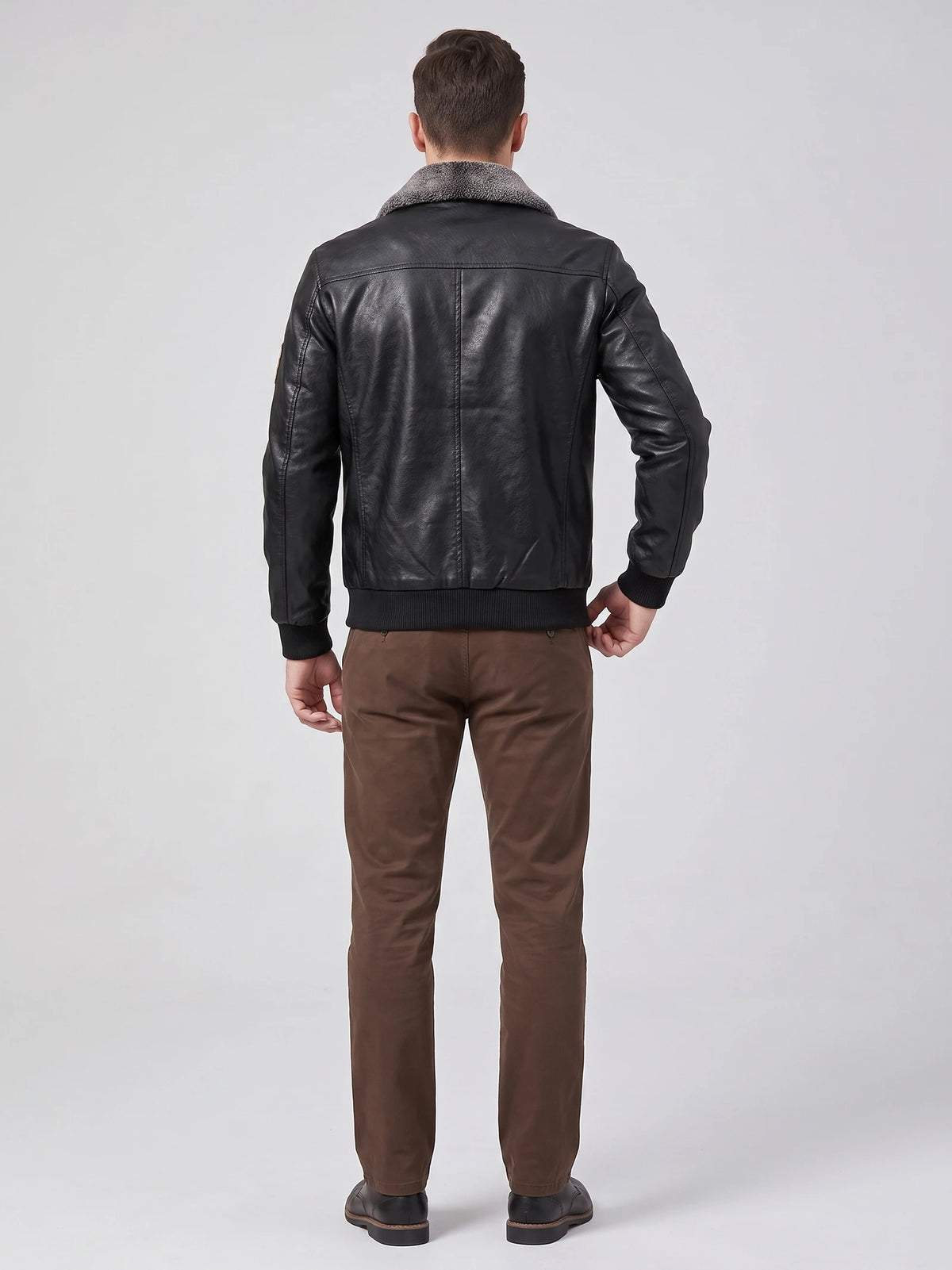 Back view of a model wearing a Black Leather Jacket with a textured fur collar, ribbed hem and cuffs, and vertical back seam detailing.