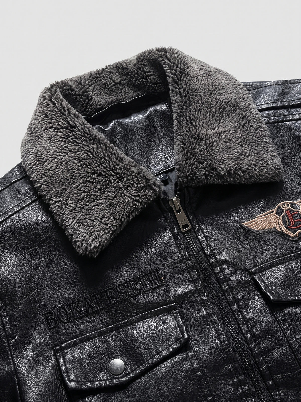 Close-up of a Black men's Leather Jacket with a plush fur collar, front zipper, and snap-flap chest pocket.