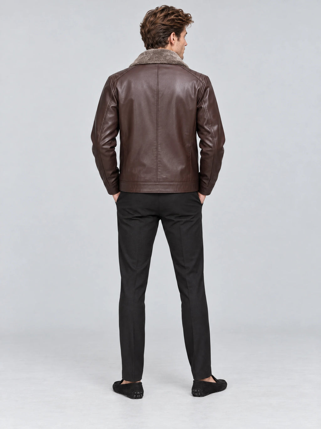 Rear studio view of a model wearing a Brown Leather Moto Jacket with a plush collar, shoulder stitching, and a center back seam.