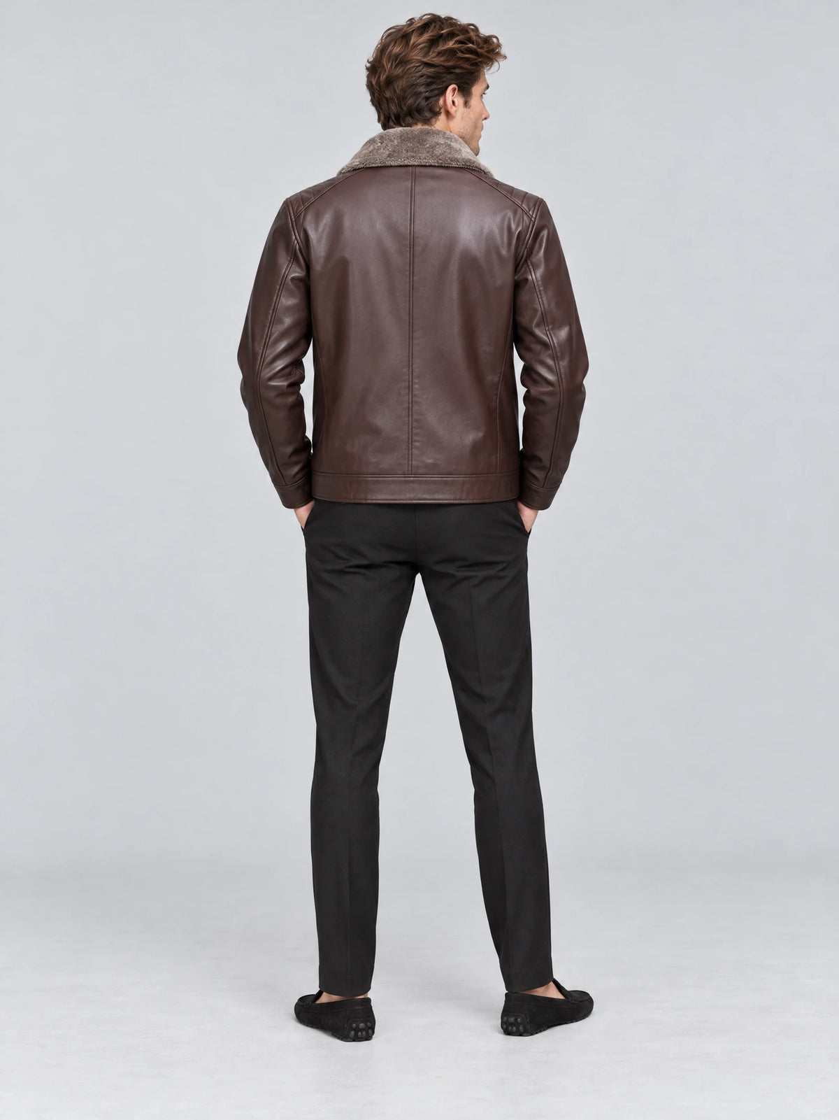 Rear studio view of a model wearing a Brown Leather Moto Jacket with a plush collar, shoulder stitching, and a center back seam.