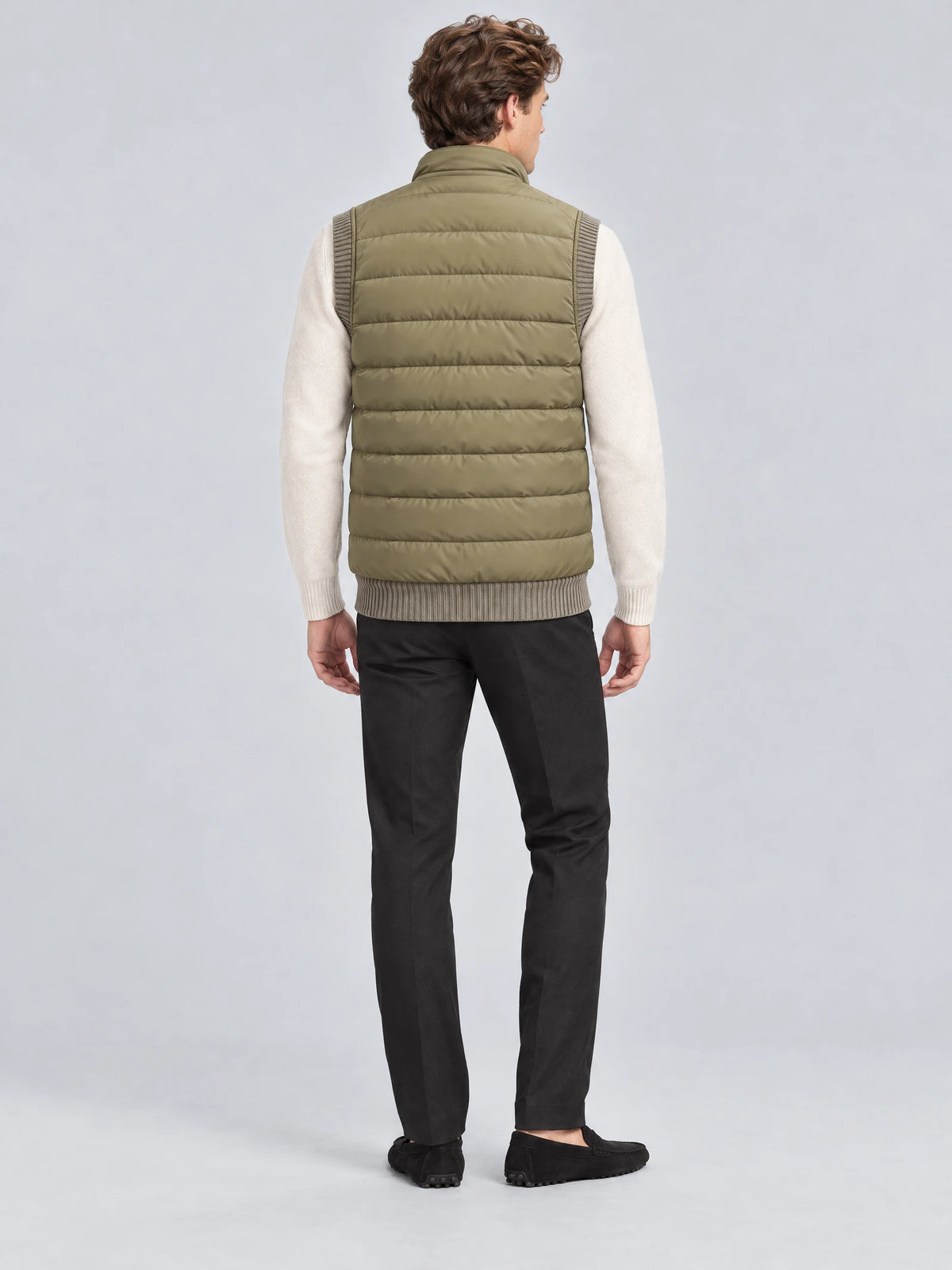 Rear studio view of a model wearing a Green lightweight puffer vest with horizontal quilted padding and a stand collar.