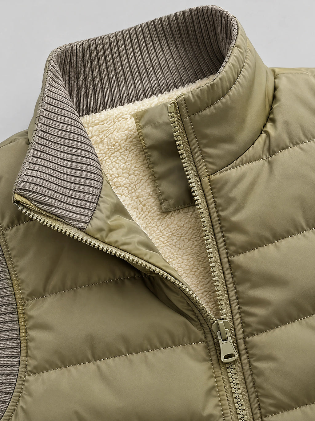 Khaki lightweight puffer vest close-up showing the ribbed collar, front zipper, quilted stitching, and soft inner lining.
