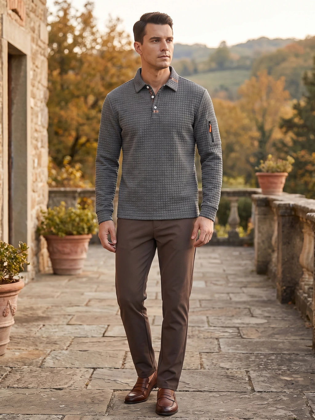 Man wearing a Gray long sleeve polo with textured fabric and a sleeve zip pocket on a stone terrace.