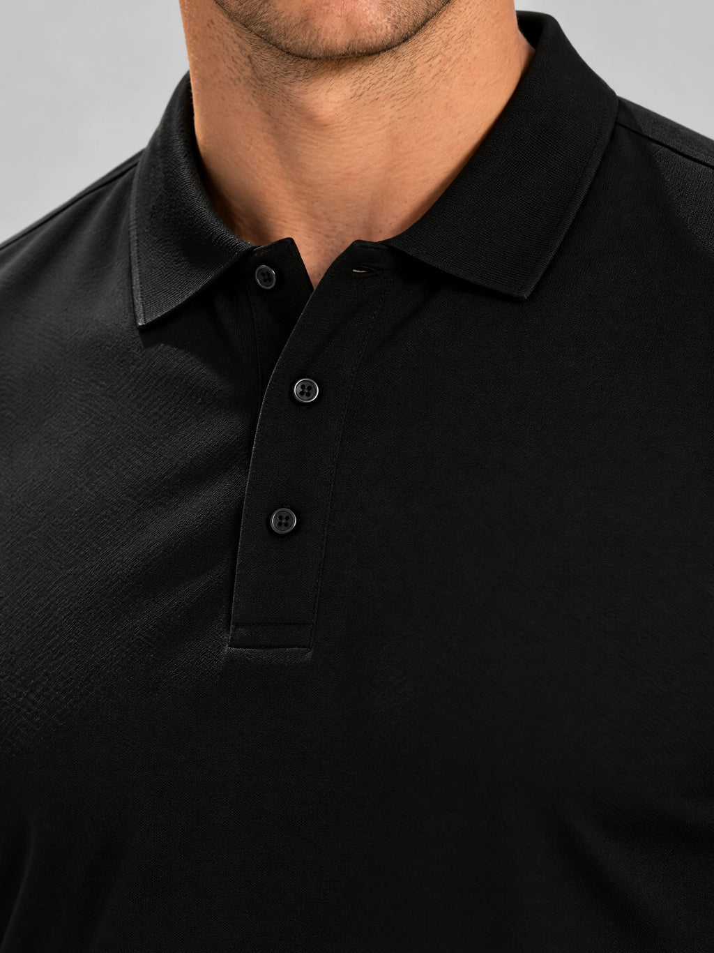 Close-up of the Black Long Sleeve Polo showing its pointed collar, three-button placket, and textured fabric.