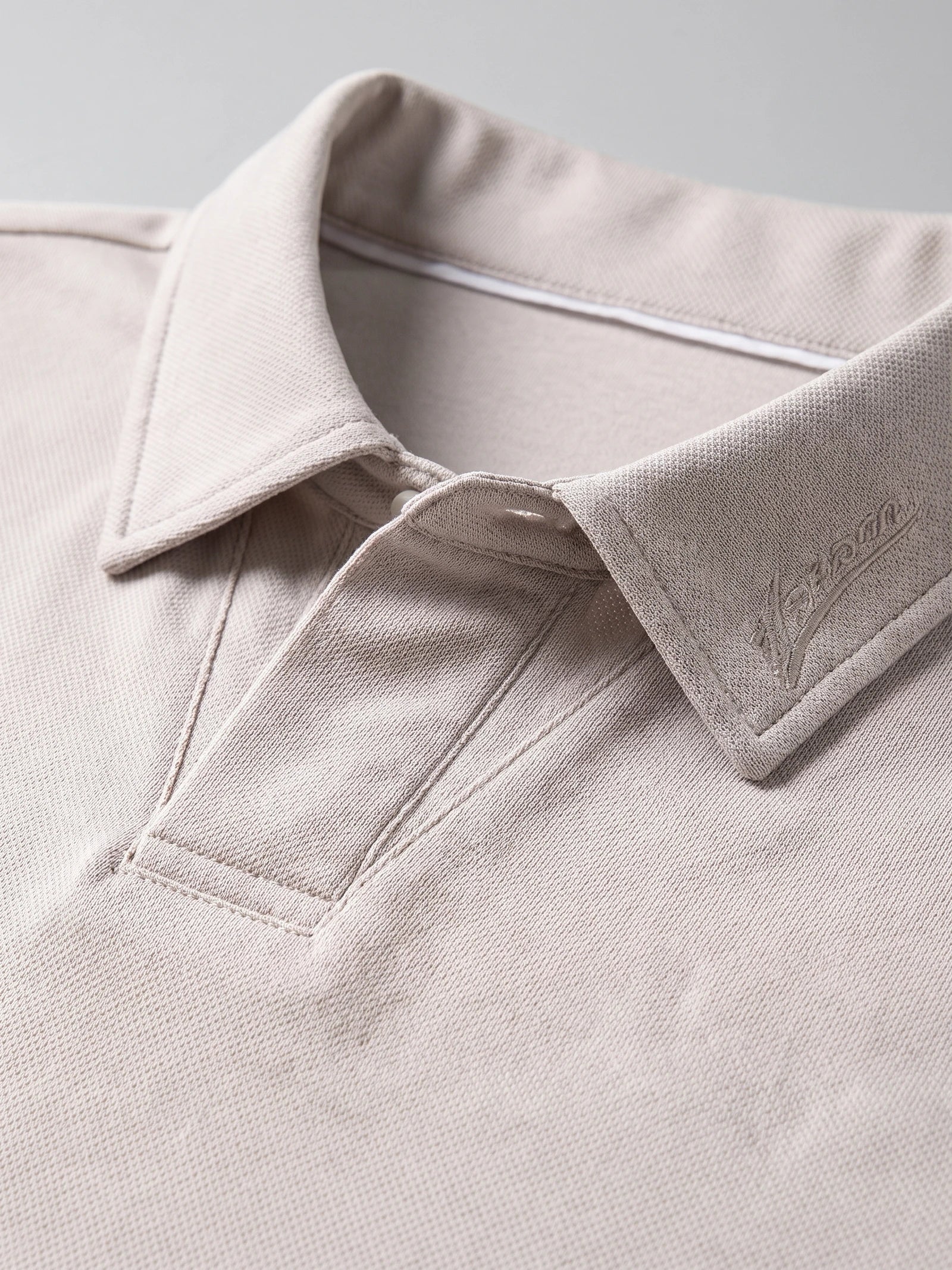 Beige Long Sleeve Polo close-up showing the textured turn-down collar, embroidered detail, and button placket.