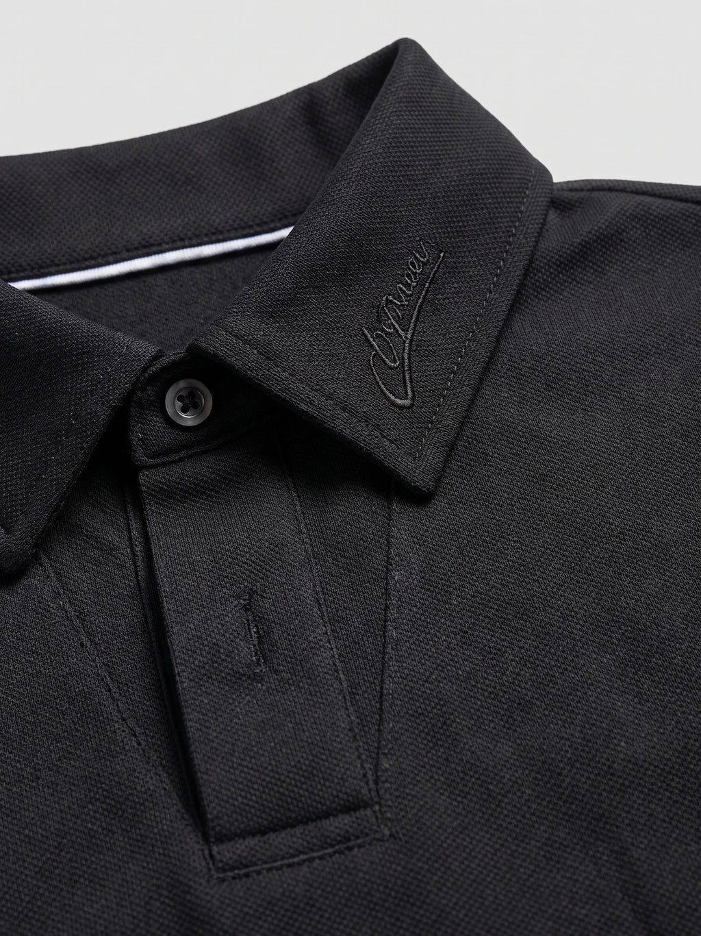 Close-up of the Black Long Sleeve Polo collar, showing tonal embroidery, textured fabric, and button placket.