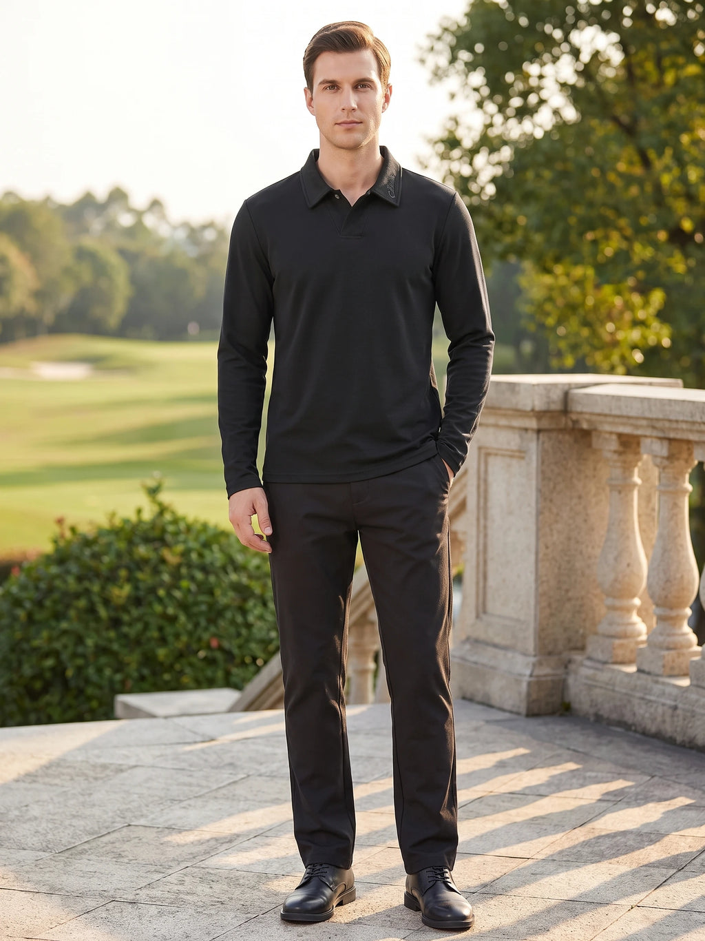 Model wearing a Black long sleeve polo shirt with a turn-down collar on a sunlit terrace beside a landscaped lawn.