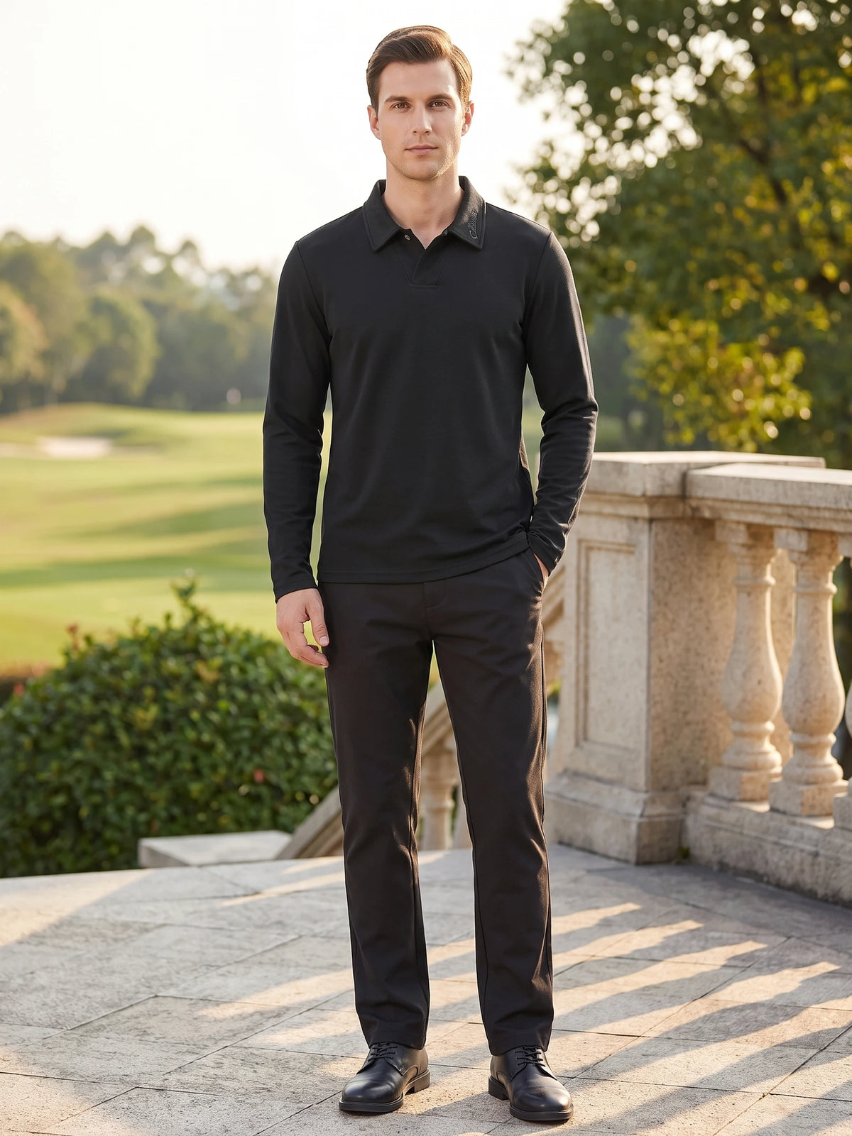 Model wearing a Black long sleeve polo shirt with a turn-down collar on a sunlit terrace beside a landscaped lawn.