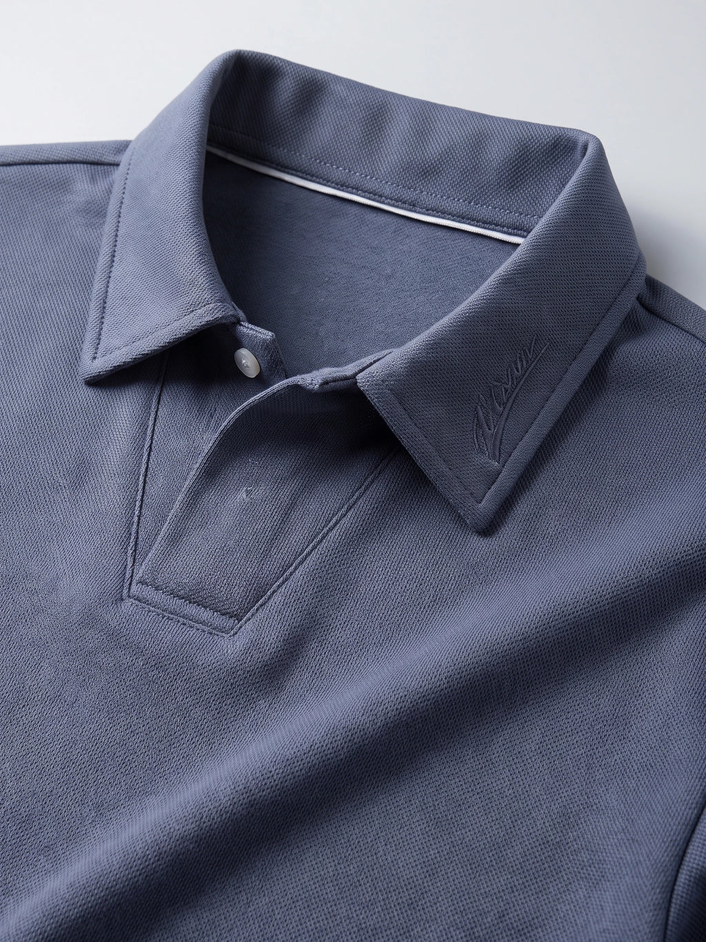 Close-up of the Blue men’s long sleeve polo collar with tonal embroidery, button placket, and textured knit fabric.