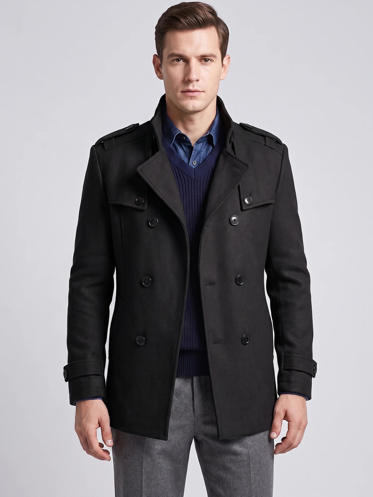 Front studio view of a model wearing a Black wool overcoat with a double-breasted button closure, wide lapels, and shoulder epaulets.