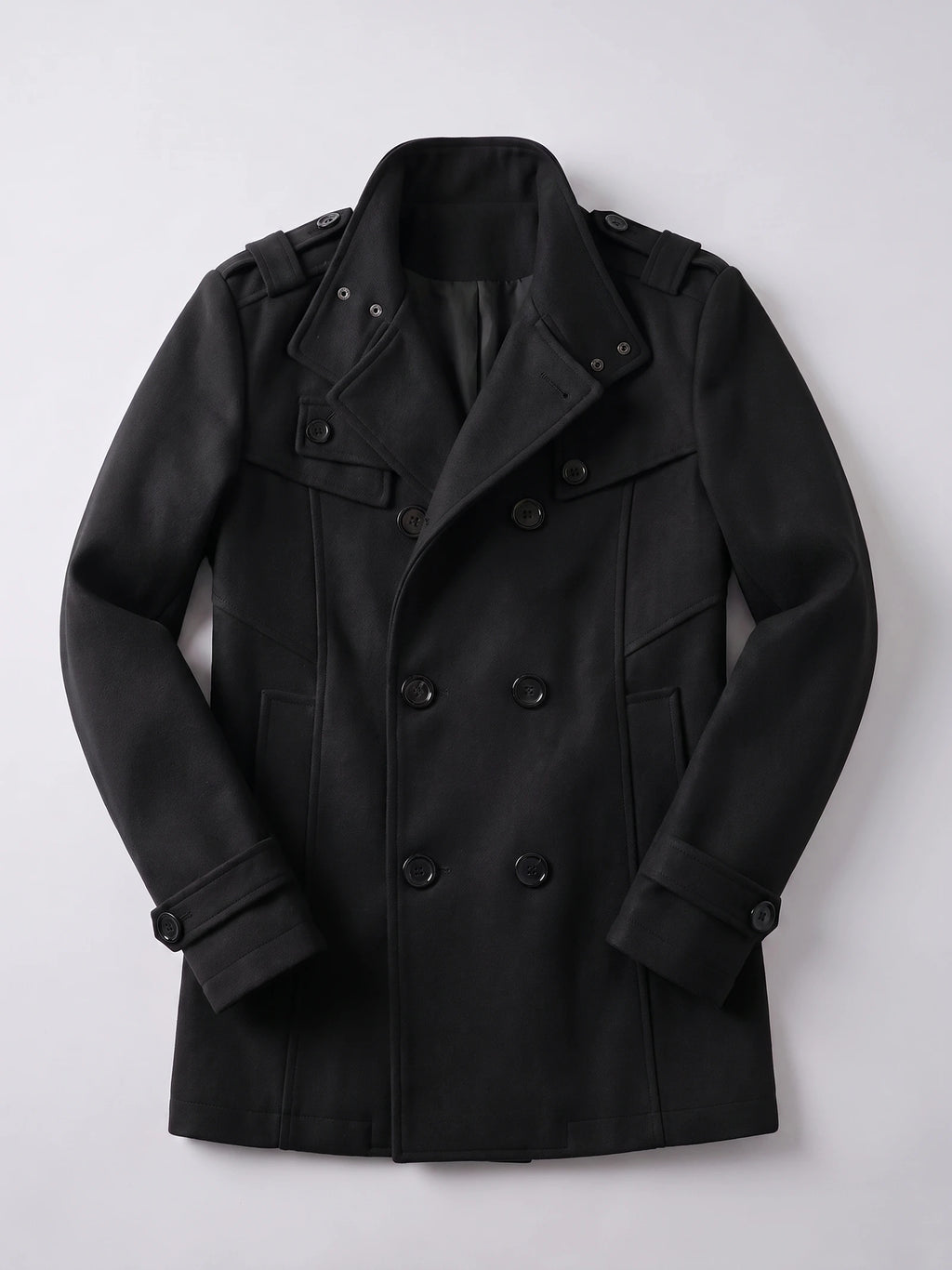 Black wool men’s overcoat laid flat, featuring a double-breasted button front, wide collar, shoulder tabs, and cuff straps.