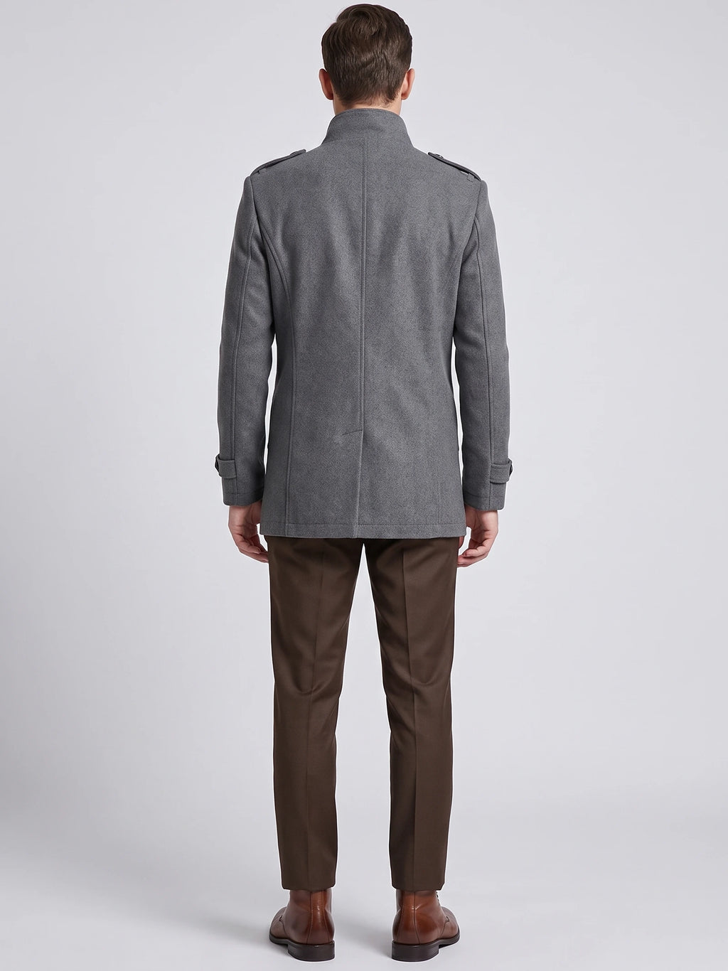 Rear studio view of a model wearing a Gray wool overcoat with a stand collar, shoulder tabs, and cuff straps.