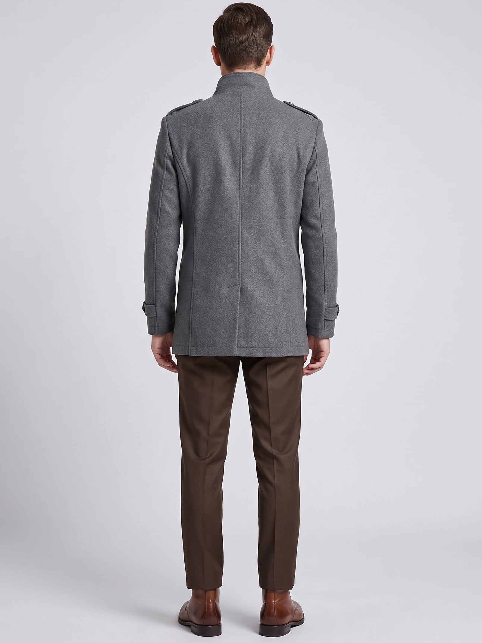 Rear studio view of a model wearing a Gray wool overcoat with a stand collar, shoulder tabs, and cuff straps.