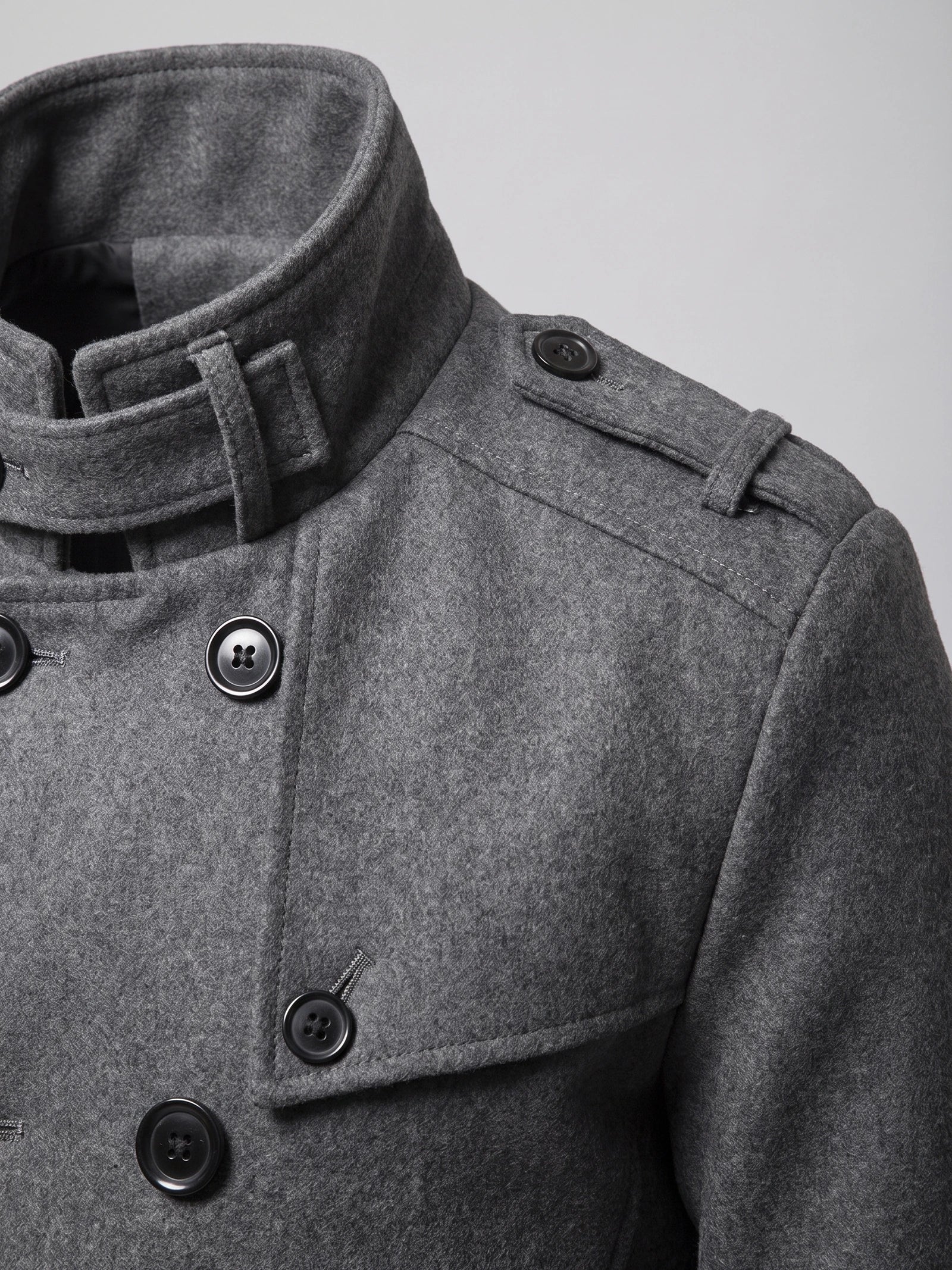 Close-up of a Gray wool Overcoat with a buckled stand collar, shoulder epaulet, and double-breasted buttons.