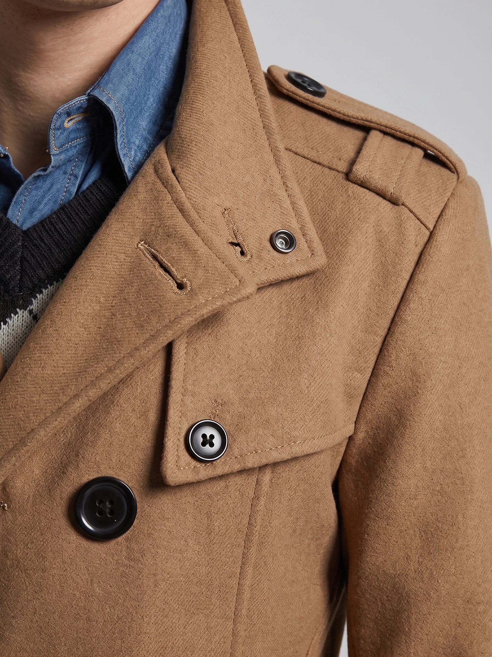 Close-up of a Khaki wool overcoat showing the wide lapel, double-breasted buttons, and shoulder epaulette.