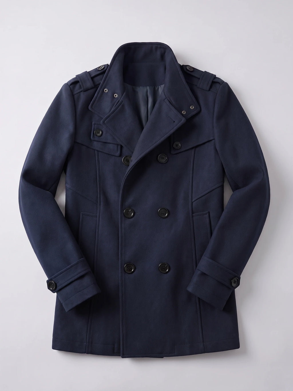 Navy wool men's overcoat laid flat, showing a double-breasted button front, wide collar, shoulder tabs, and belted cuffs.
