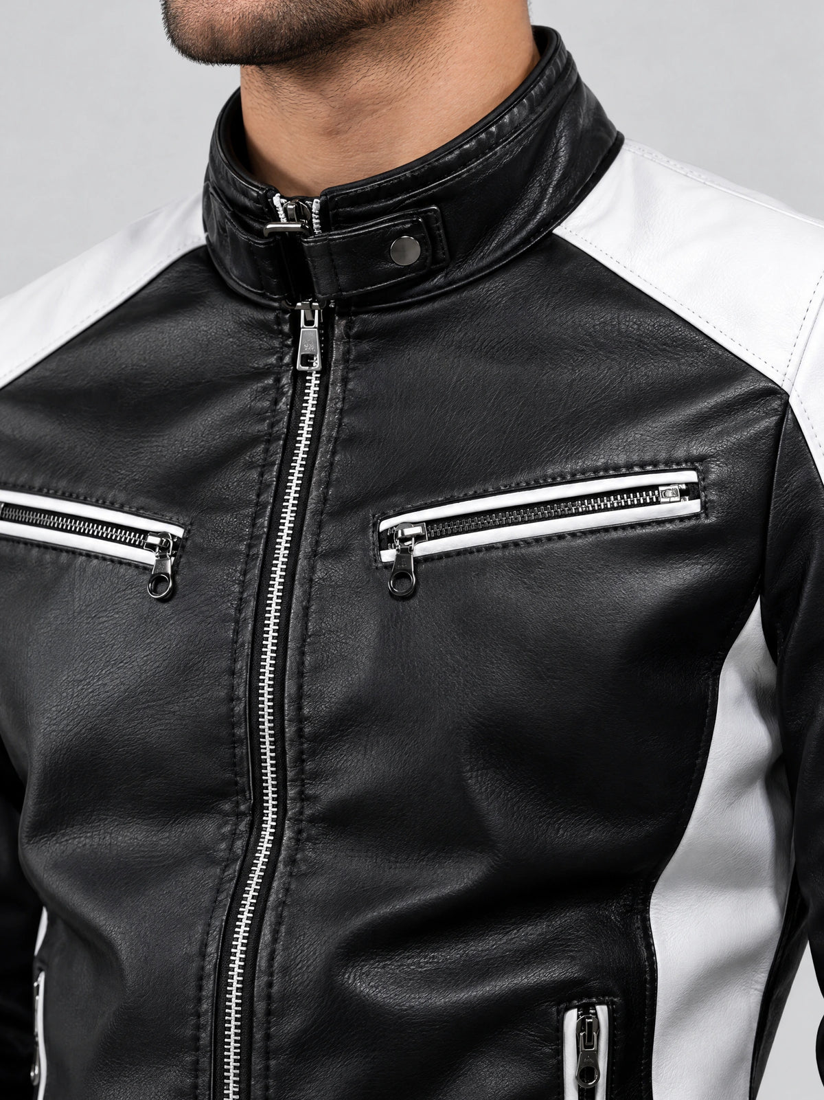 Black Moto Leather Jacket close-up showing the snap-tab stand collar, front zipper, and zippered chest pockets.