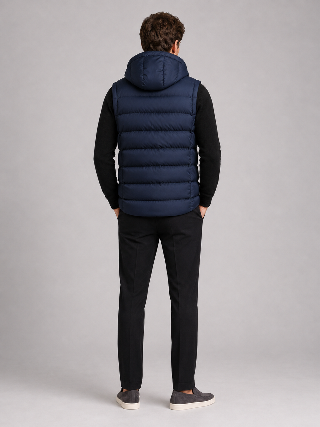 Back view of a man wearing a navy hooded puffer vest showing the attached hood, padded construction, sleeveless cut, and comfortable fit