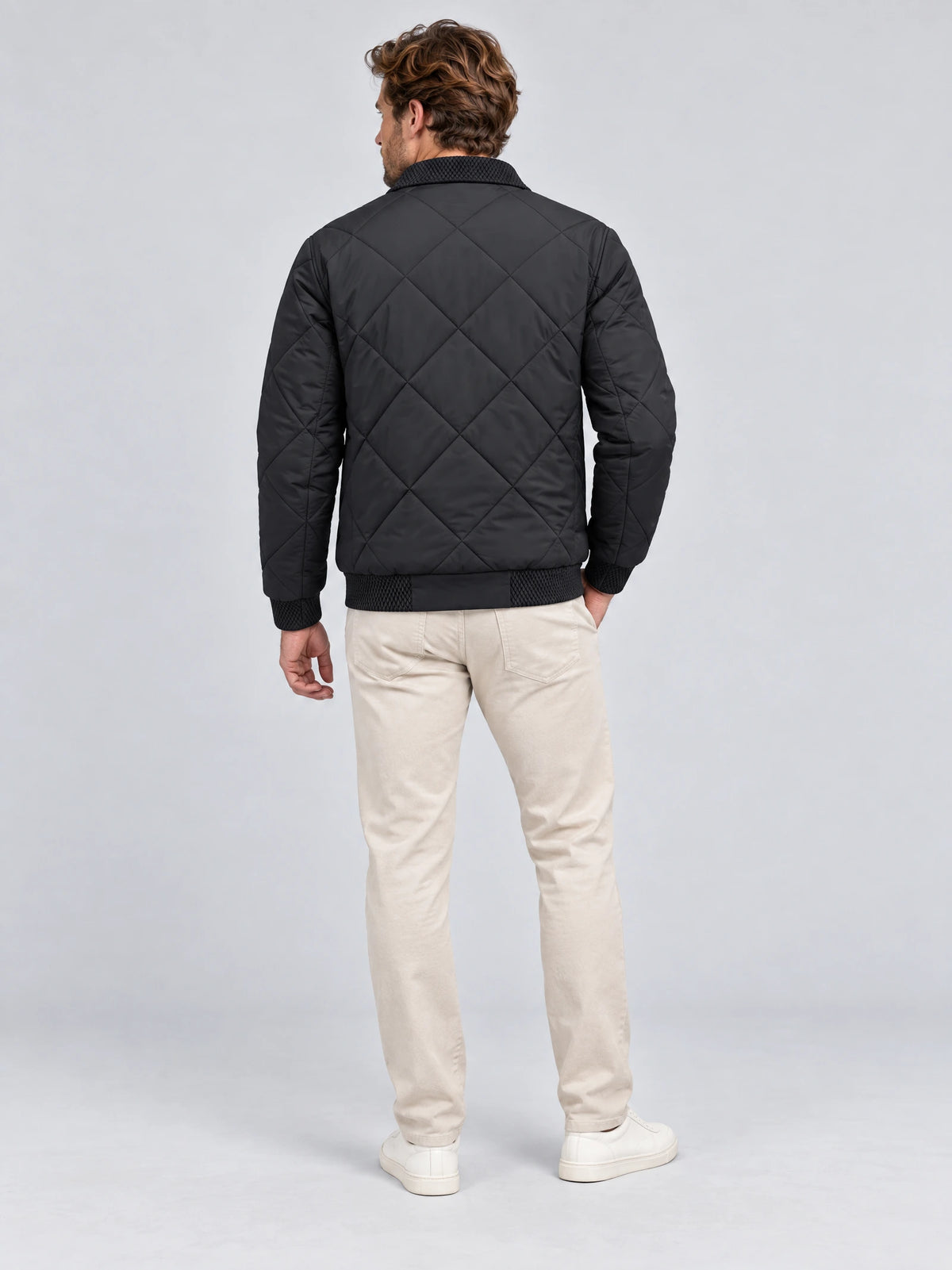 Back view of a model wearing a Black men's padded lapel jacket with diamond quilting and ribbed trim.