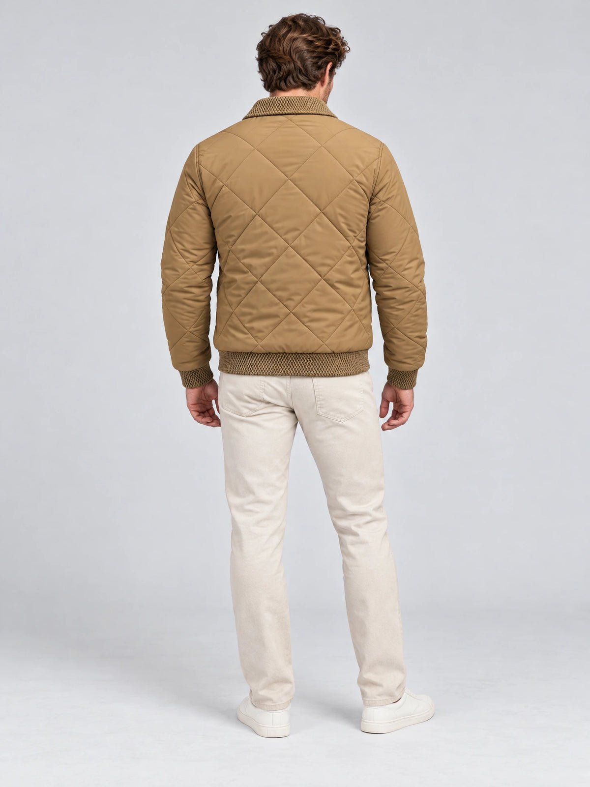 Back view of a model wearing a Khaki men's padded lapel jacket with diamond quilting and ribbed trim.