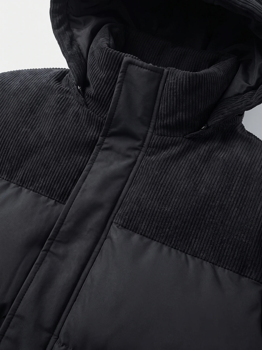 Close-up of the Black Padded Puffer Jacket showing the ribbed high collar, zipper placket, and quilted polyester panels.