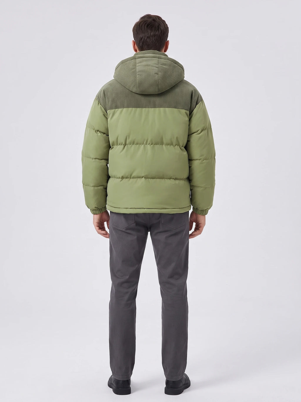 Rear studio view of a model wearing a Green padded puffer jacket with a hood, ribbed upper back panel, and quilted insulation.