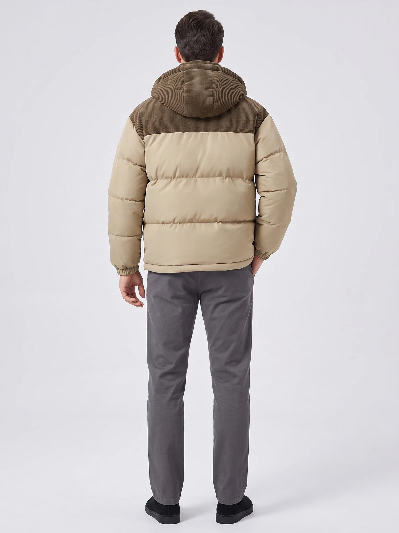 Rear studio view of a model wearing a Khaki padded puffer jacket with a hood, quilted back panels, and elasticated cuffs.