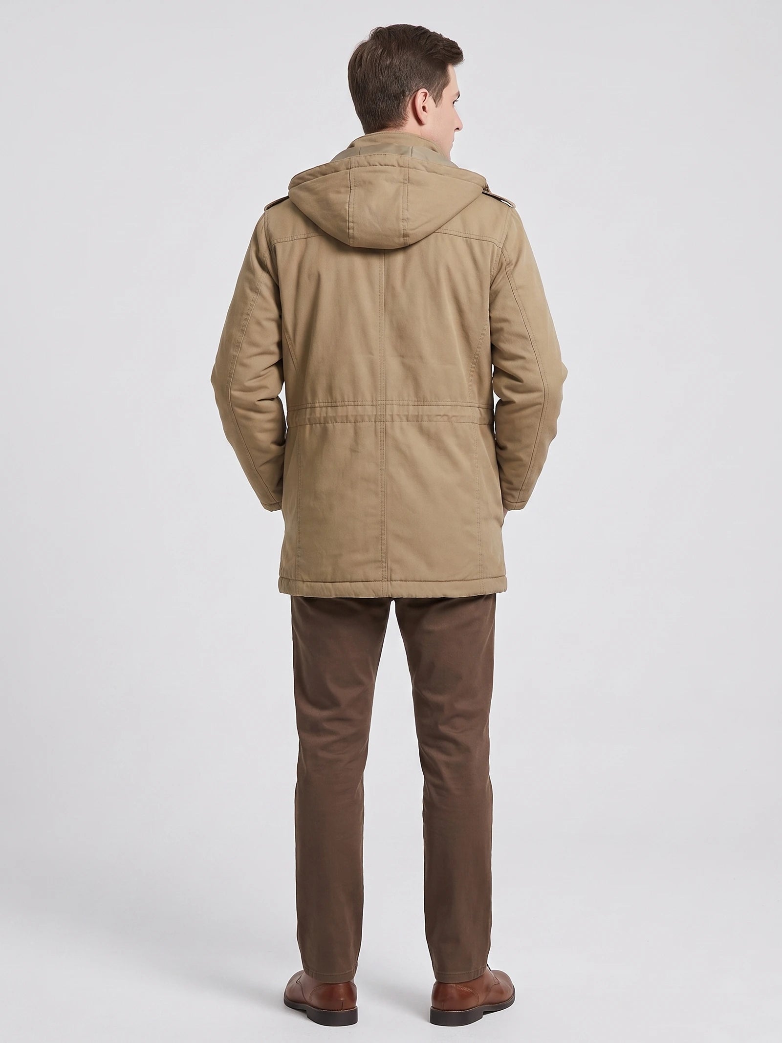 Rear studio view of a model wearing a Khaki men's Parkas jacket with a hood, long sleeves, and back seam detailing.