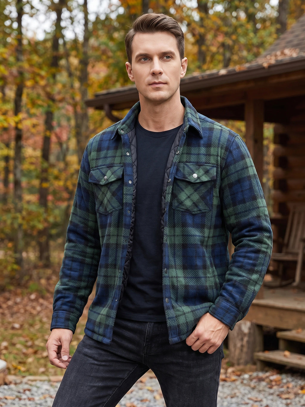 Model wearing a Green plaid Flannel Jacket with snap chest pockets outside a rustic cabin in an autumn woodland.