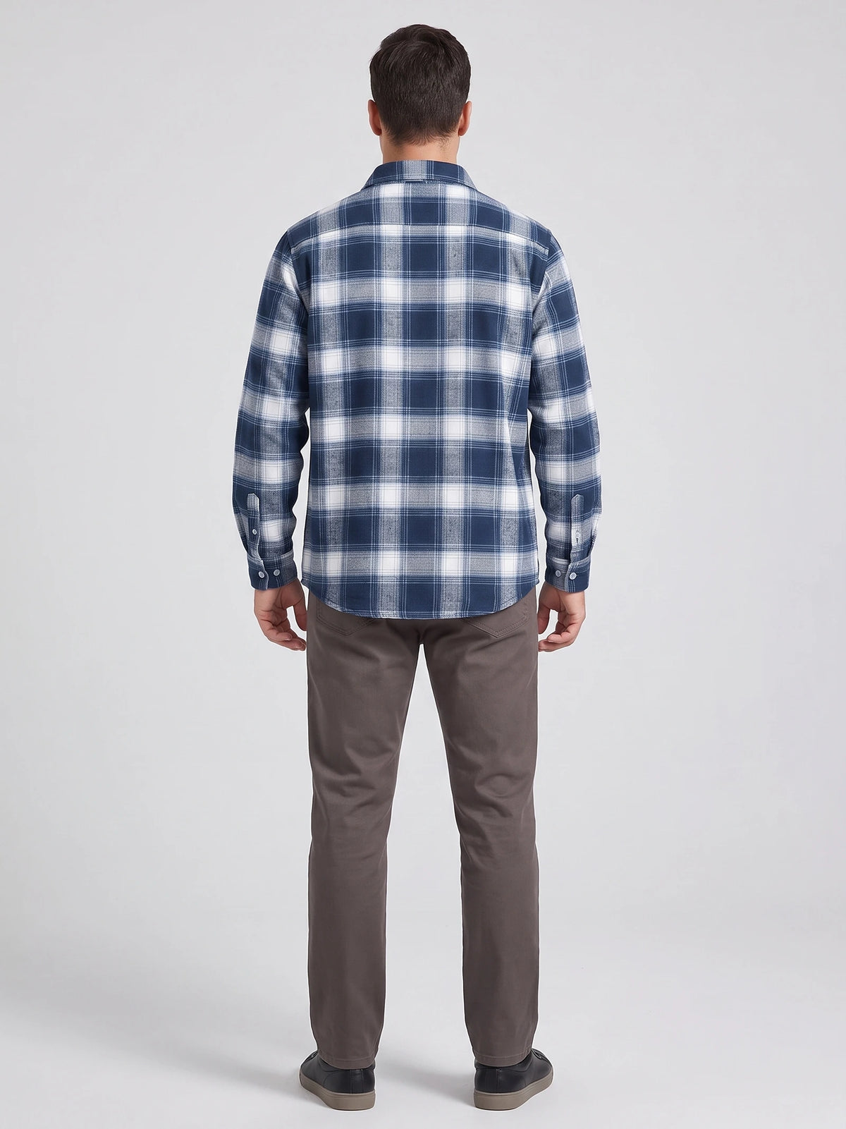 Rear studio view of a model wearing a Blue plaid flannel shirt with long sleeves and button cuffs.