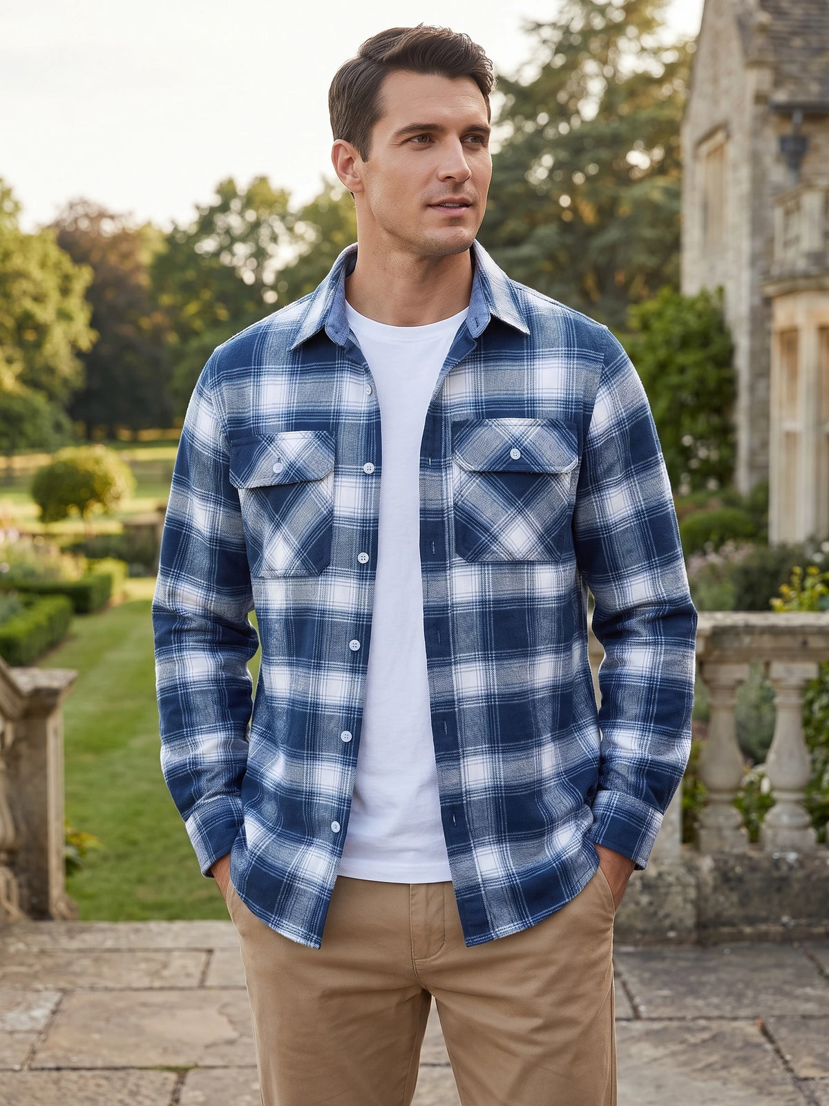 Model wearing a Blue plaid flannel shirt jacket with buttoned chest pockets in a landscaped garden setting.