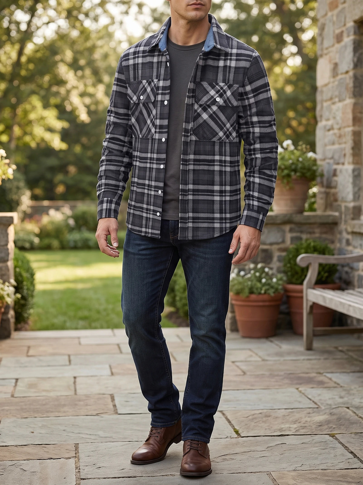 Model wearing a Dark Gray plaid flannel shirt jacket with buttoned chest pockets while walking on a garden patio.