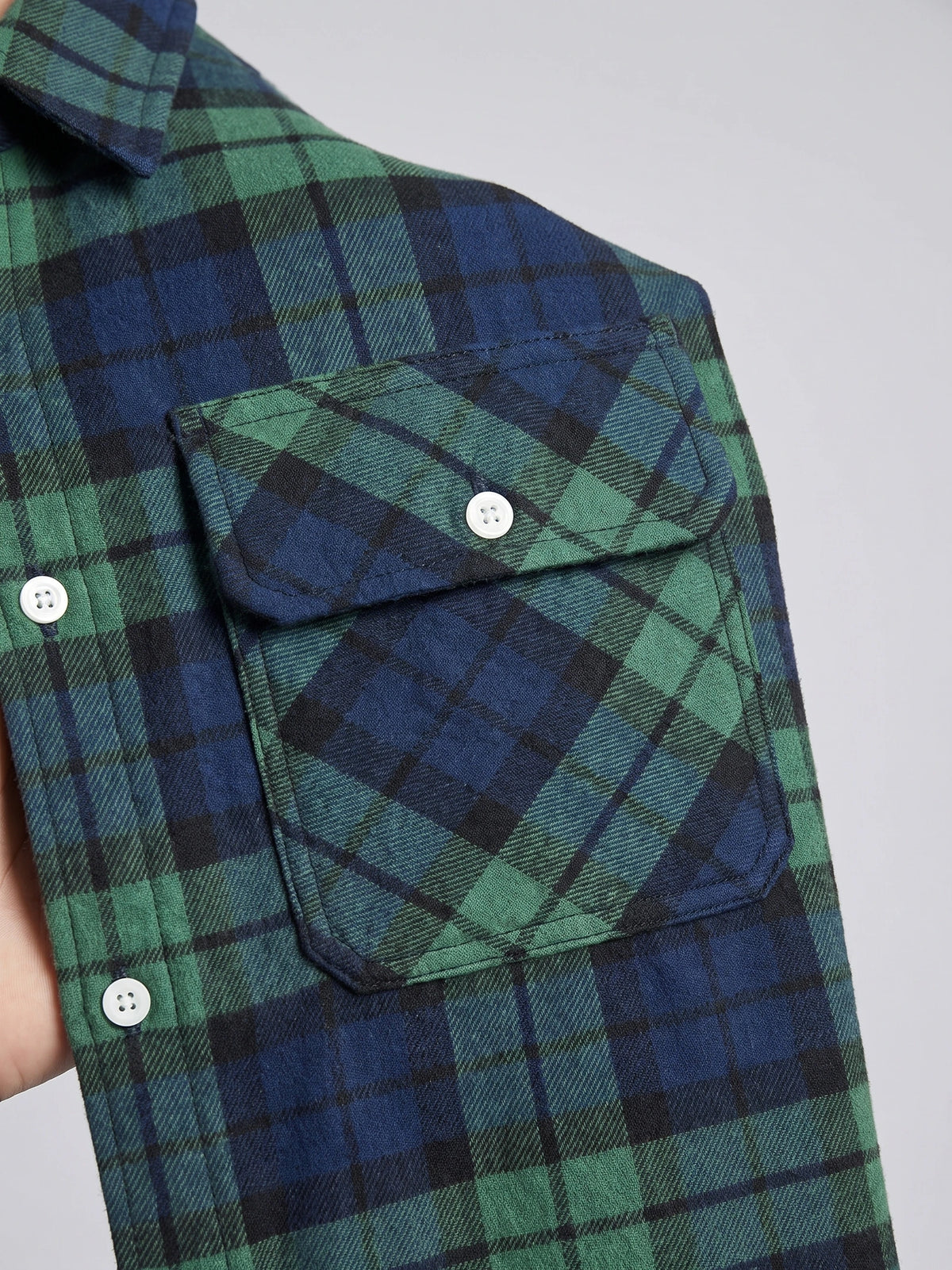 Close-up of the Green Plaid Flannel Shirt showing a buttoned chest pocket, pointed collar, and textured plaid fabric.