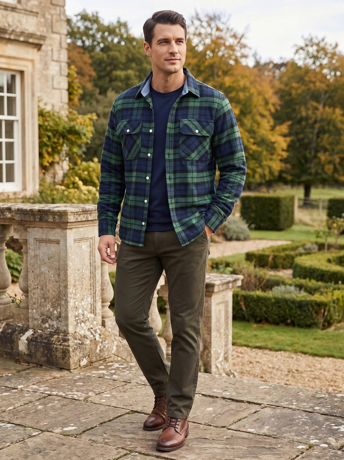 Man wearing a Green Plaid Flannel Shirt with buttoned chest pockets while walking on a stone terrace beside a garden.