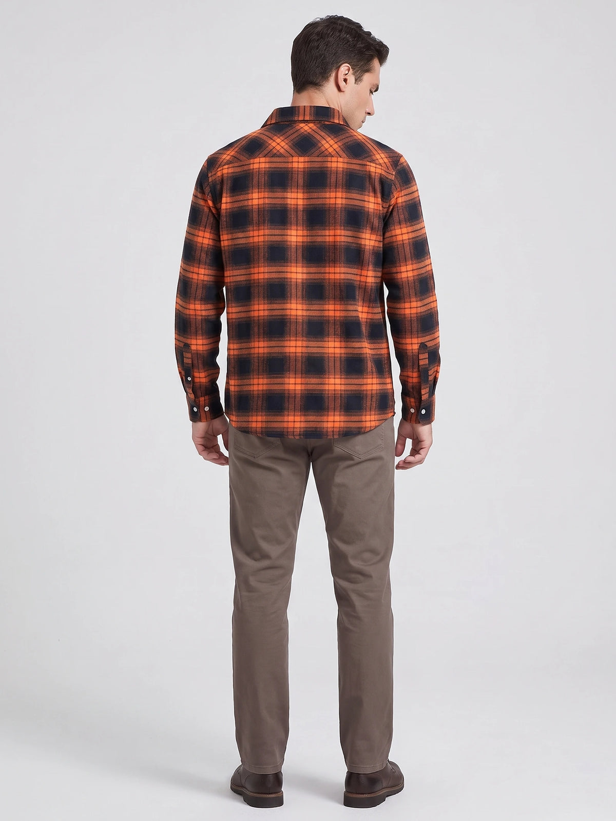 Rear studio view of a model wearing an Orange plaid flannel shirt jacket with long sleeves and a curved hem.