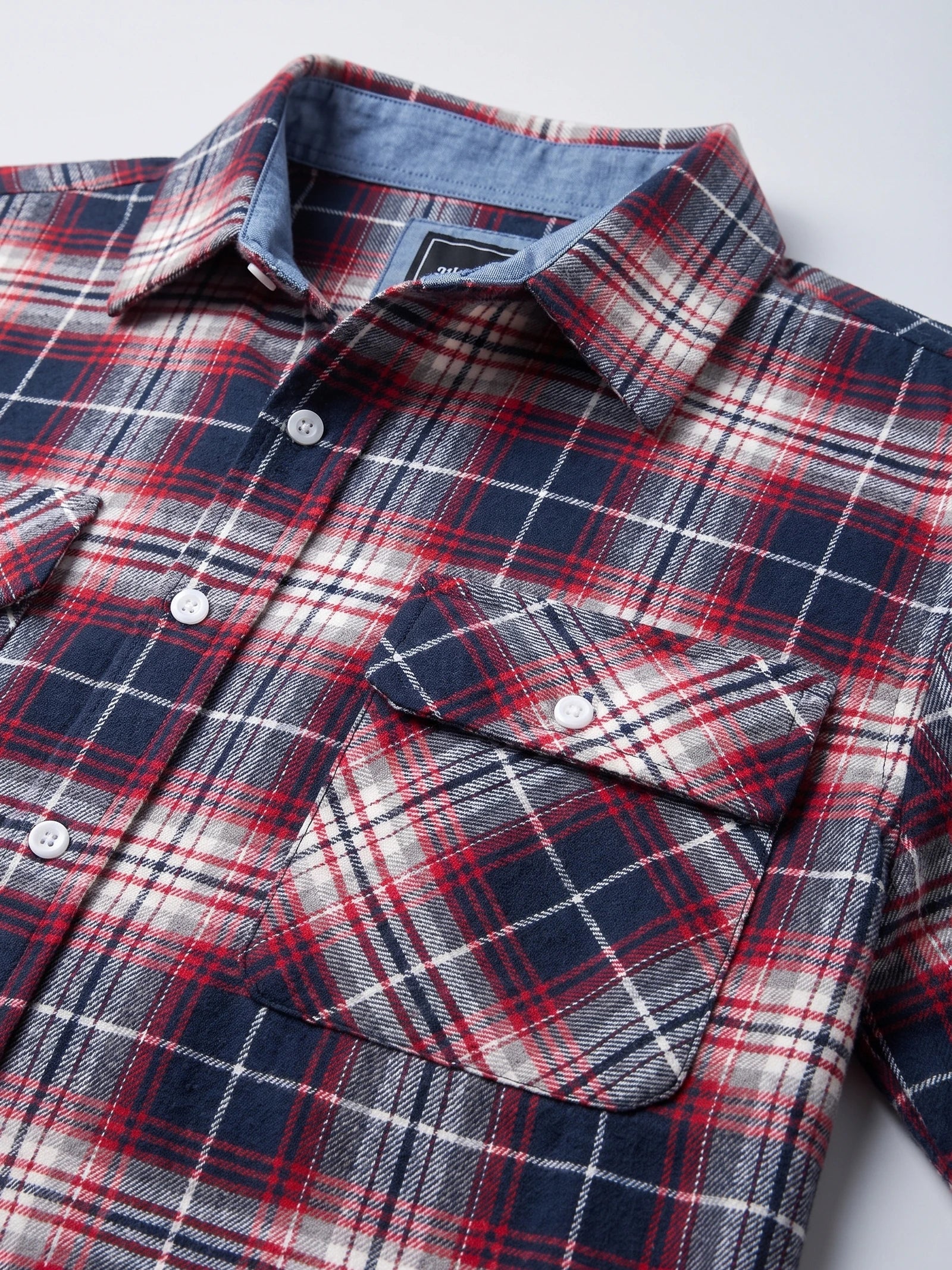 Close-up of a Red plaid flannel shirt jacket showing the pointed collar, button front, and flap chest pocket.