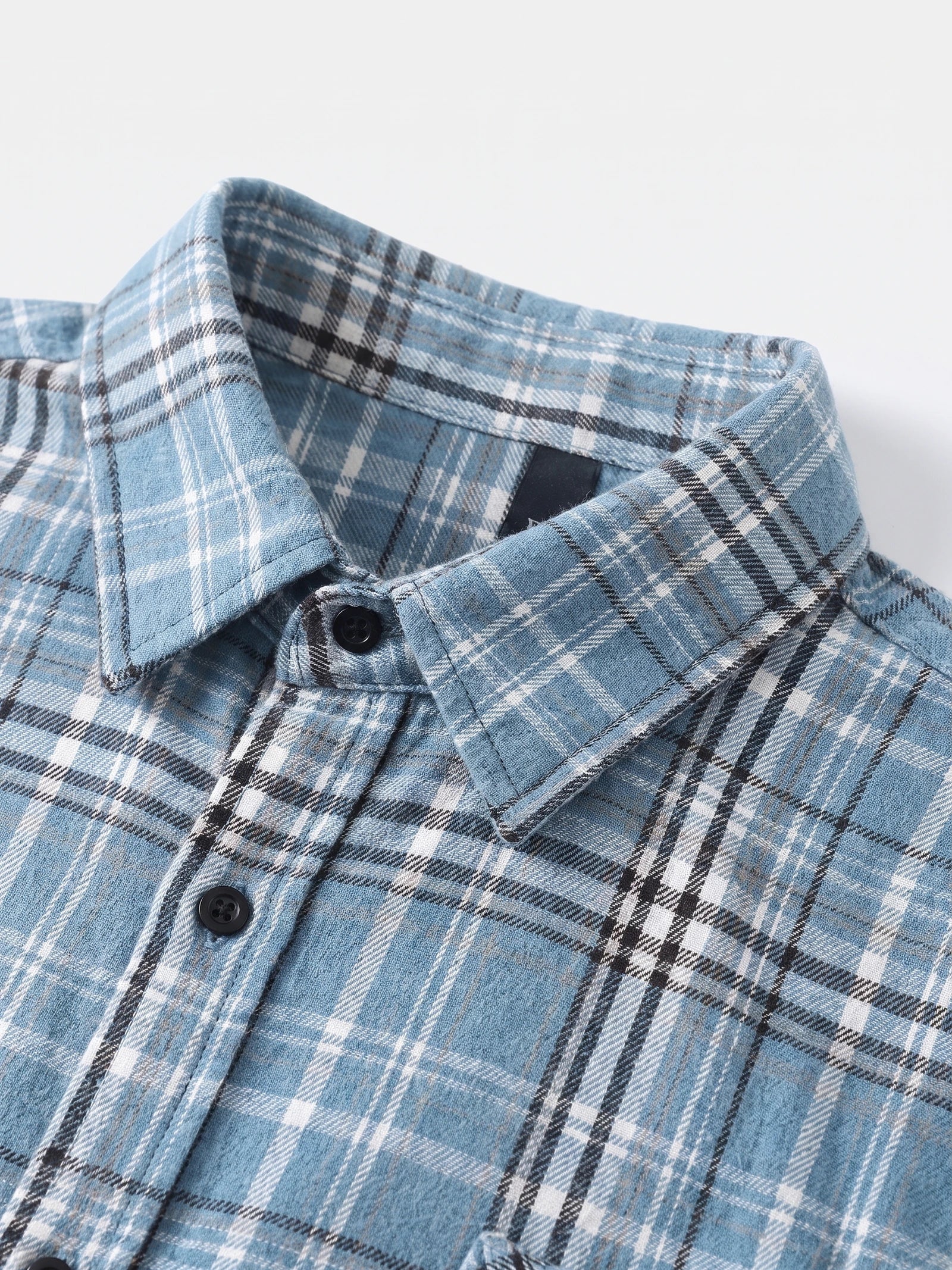 Close-up of the Blue plaid flannel shirt collar, button placket, and stitched chest pocket.