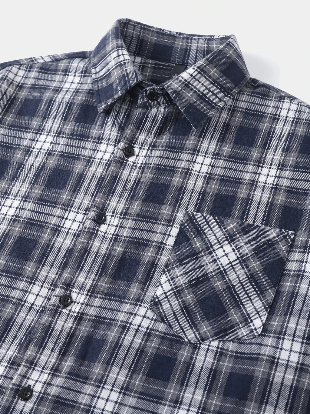 Close-up of a Navy plaid Flannel Shirt with a pointed collar, button front, and chest pocket.