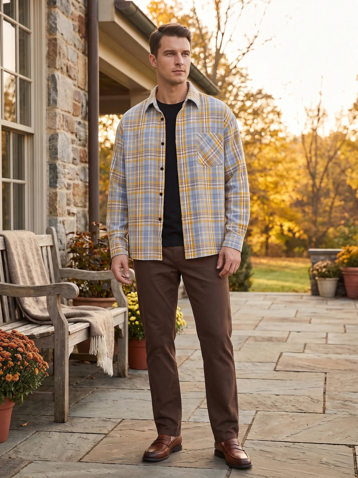 Man wearing a Yellow plaid Flannel Shirt with a chest pocket on a sunlit patio beside a stone house.