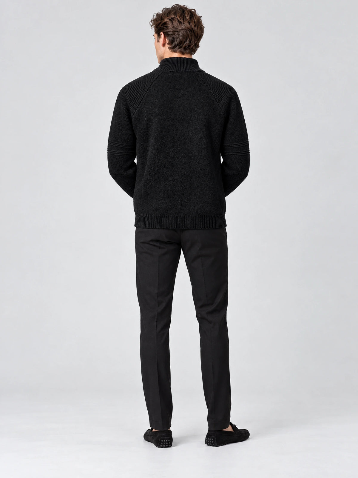 Rear studio view of a model wearing a Black men's quarter zip sweater with a ribbed stand collar and textured knit sleeves.