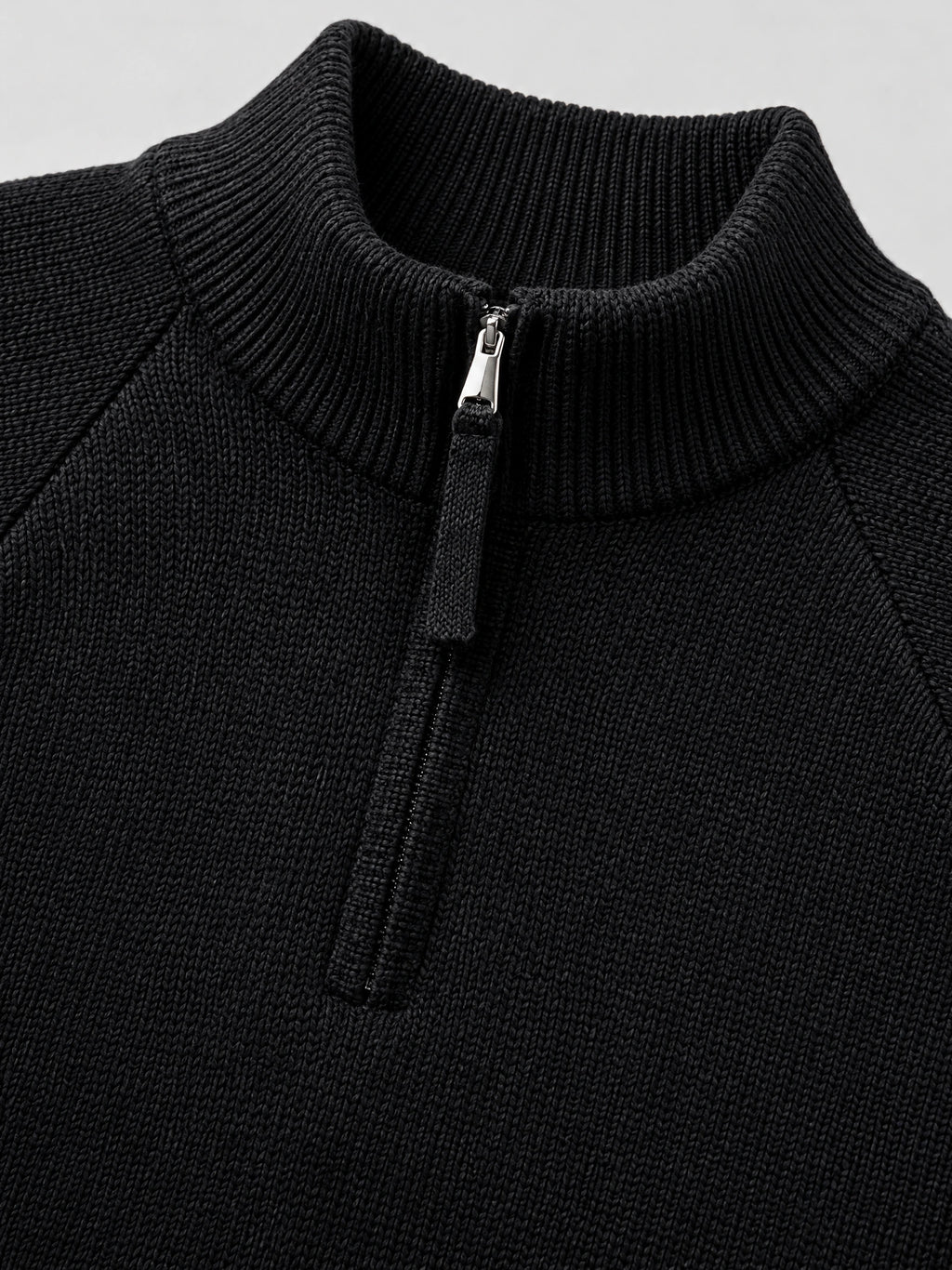 Close-up of the Black men's quarter zip sweater, showing the ribbed stand collar, knit texture, and zipper pull.